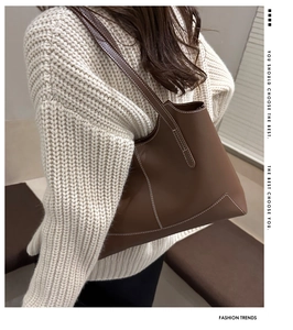 Sac fourre-tout en cuir marron avec surpiqûres blanches contrastées porté par un mannequin