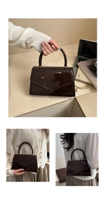 Detail of dark brown patent leather envelope bag with gold chain and woven handle