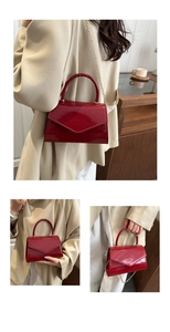 Close-up of deep red patent leather crossbody bag with glossy finish and gold chain