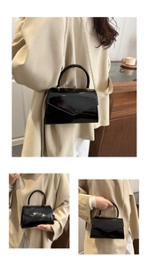 Detail of a black patent leather handbag with a V-shaped flap and gold chain strap
