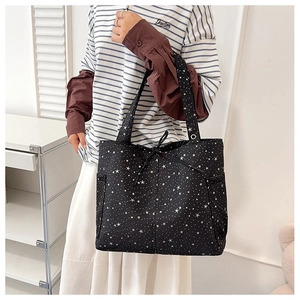 Detalle del bolso tote negro con estrellas, lazo decorativo y prácticos bolsillos laterales