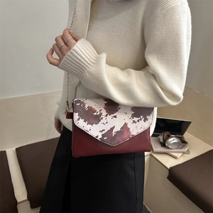 Fashionable cow print flap shoulder bag with brown patchwork and gold chain strap