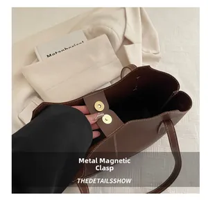 Détail du fermoir magnétique doré sur sac fourre-tout en cuir marron avec surpiqûres