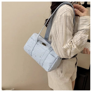 Detail view of light blue canvas shoulder bag featuring silver star patterns and side pocket