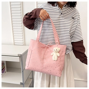 Dettaglio della borsa tote rosa in tela con stelle argento, fiocco e ciondolo orsetto