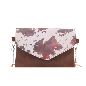 Fashionable cow print crossbody bag with brown leather panel and gold chain strap