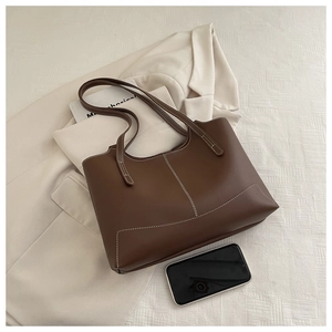 Gros plan d'un sac cabas en cuir marron avec surpiqûres blanches contrastées et doubles anses
