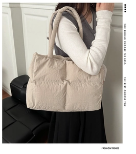 Detail of beige quilted puff tote bag with soft padded texture and shoulder strap