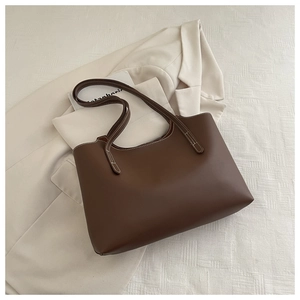 Détail d'un sac cabas marron avec coutures contrastées blanches sur un blazer beige