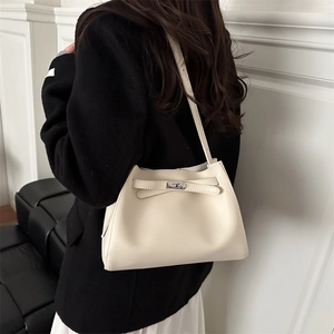 Creamy white leather handbag with metal turn-lock closure shown on a model in black blazer