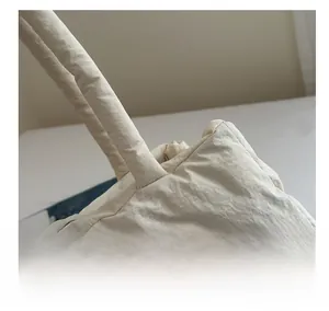 Detail of high-quality stitching on beige quilted tote bag showing nylon texture