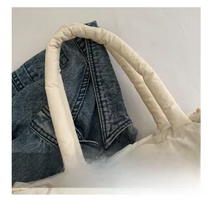 Close-up of padded quilted handle and stitching detail on off-white puffer tote bag