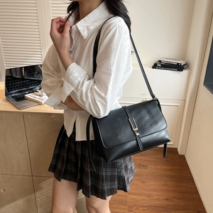 Retro black leather shoulder bag with gold buckle shown on model in a casual setting
