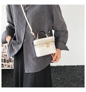 Detail of white crocodile embossed box bag with gold zippers and slim top handle
