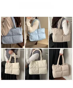 Detail view of large quilted puffer tote bag showing light blue and beige fabric texture