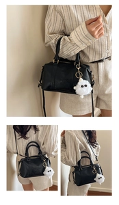 Detail der schwarzen Boston-Handtasche mit goldener Hardware und Plüsch-Anhänger