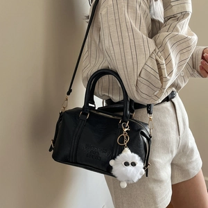 Minimalist black PU leather Boston bag with gold zippers and a plush charm on strap