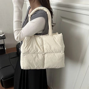 Minimalist creamy white quilted puffer tote bag for women shown on a shoulder