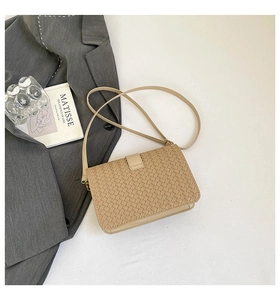 Gros plan sur le sac baguette tissé beige avec texture en losange et rabat élégant