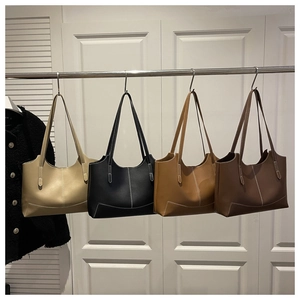 Détail de quatre sacs cabas minimalistes en cuir en blanc cassé, noir, marron et fauve