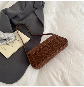 Detailed texture of brown leopard print faux pony hair baguette shoulder bag on blazer