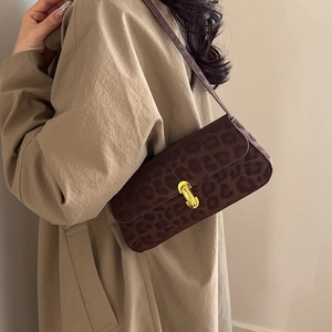 Elegant leopard print baguette shoulder bag with gold clasp shown on a model