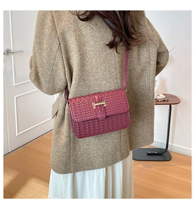 Dettaglio della borsa in pelle intrecciata bordeaux con fibbia H dorata sulla modella