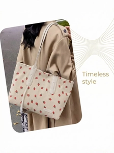 Detail of strawberry print corduroy tote bag worn over the shoulder with a trench coat