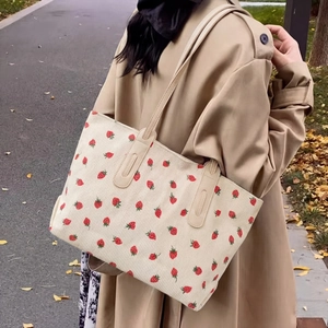 Minimalist tote bag with strawberry print and corduroy texture on female model shoulder