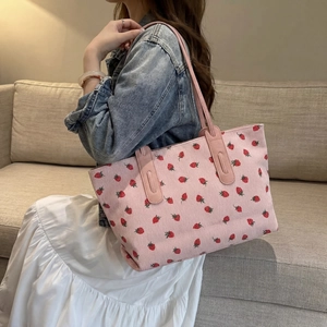 Detail of pink corduroy tote bag featuring cute strawberry prints and long leather handles