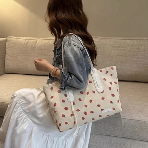 Detailed side view of a strawberry corduroy tote bag worn over the shoulder