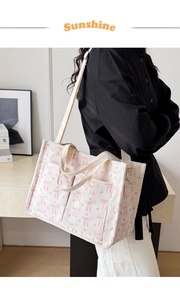 Detail view of corduroy tote bag with pink bow patterns and dual front pockets