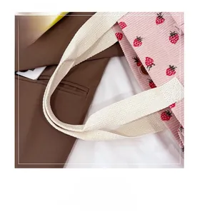 Detail of pink corduroy strawberry tote featuring durable cream cotton webbing handles