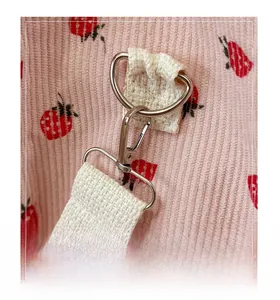 Detail of silver metal lobster clasp and D-ring on pink corduroy strawberry tote bag