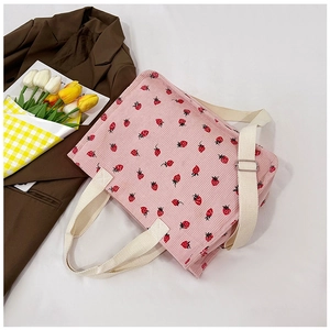 Detailed top view of pink corduroy tote bag featuring red strawberry prints and white straps