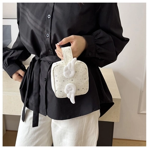 Dettaglio di una mini pochette crema con motivi a stelle e ali d'angelo in peluche