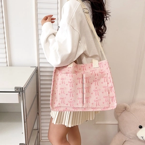 Pink corduroy tote bag with bow and heart prints featuring exterior pockets and strap