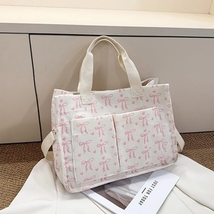 Detail of corduroy tote bag with pink ribbon bow patterns and dual front pockets