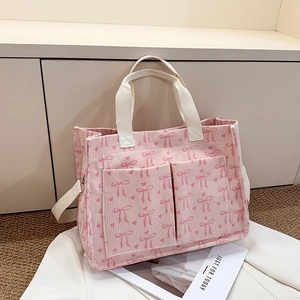 Close-up of pink corduroy tote bag featuring bow patterns and white woven handles