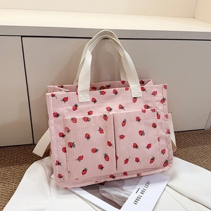 Detailed view of pink corduroy strawberry tote bag featuring multi-pocket design and canvas handles