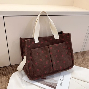 Detailed texture of brown corduroy tote with red strawberry print and front pockets