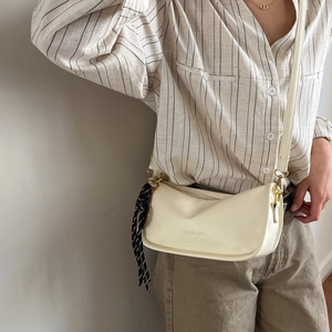 Retro cream crossbody shoulder bag with silk scarf charm shown on model in natural light