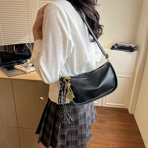 Detail of black hobo bag with gold tennis racket charm and colorful braided rope accent