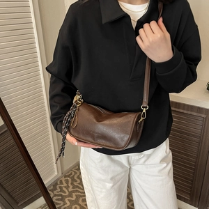 Retro dark brown cylinder crossbody bag with gold hardware worn by female model