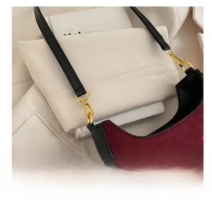 Détail du sac bandoulière en daim bordeaux avec crochet doré et broderie