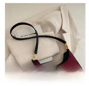 Détail du sac bandoulière en velours rouge avec broderie nœud et crochets dorés
