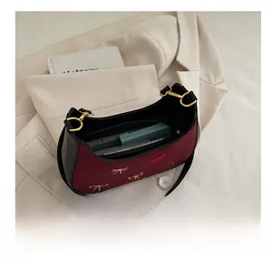 Vue détaillée d'un sac hobo en daim bordeaux montrant la capacité et les broderies