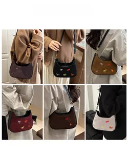 Détail des sacs bandoulière en suédine avec broderie de nœuds colorés en plusieurs coloris