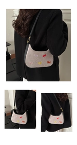 Détail de broderie nœud coloré et dorures sur sac hobo croissant en daim gris