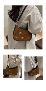 Détails du sac croissant en daim avec nœuds brodés colorés et bandoulière en cuir noir